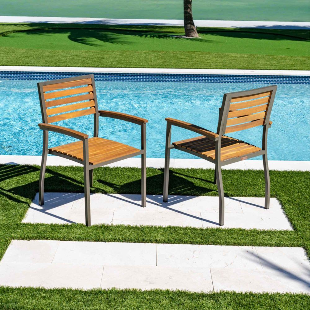 Two wooden chairs by a poolside on a grassy area