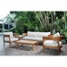 Outdoor furniture set with wooden frames and white cushions in a garden setting.