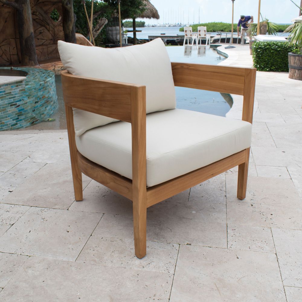 Wooden chair with white cushions on a patio area near a pool.