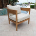Wooden chair with white cushions on a patio area near a pool.