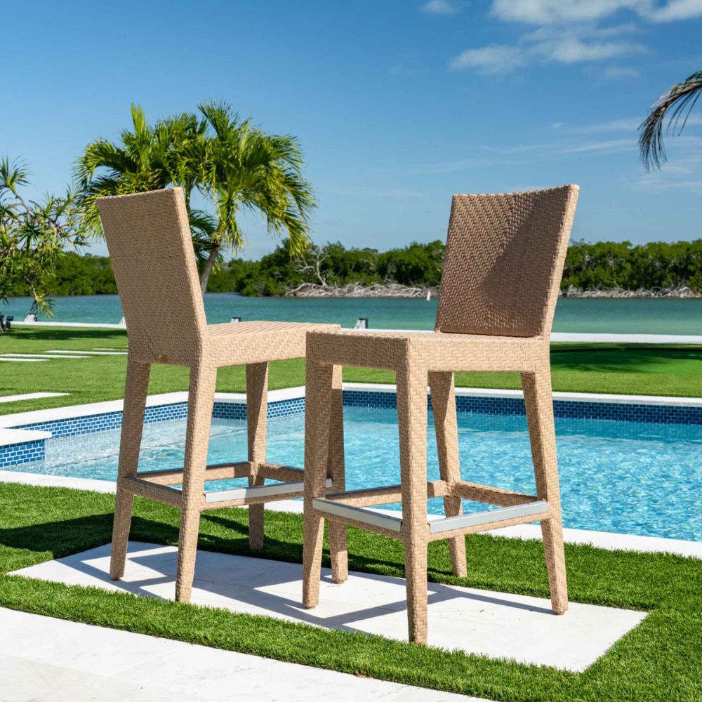Two wicker bar stools by a pool with a scenic background