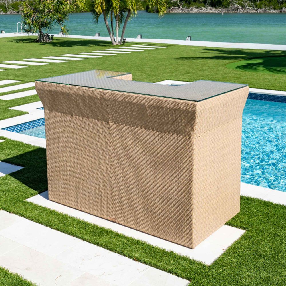 Wicker bar with glass top on a grassy area by a pool