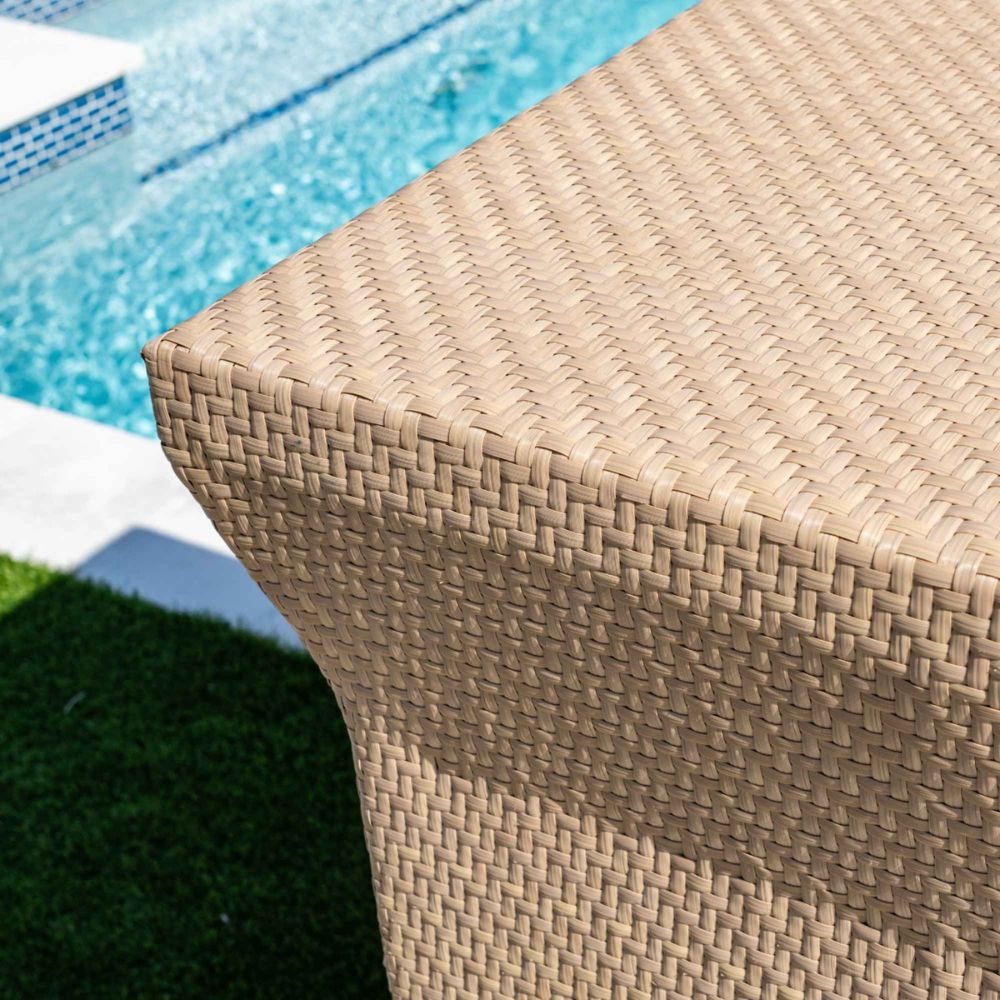 Close-up of a woven outdoor stool with a pool in the background