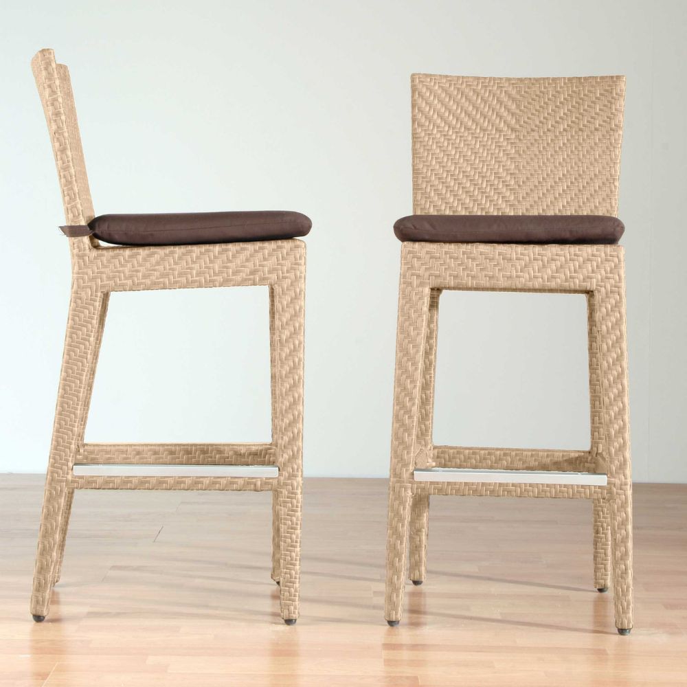Two wicker bar stools with brown cushions on a light wooden floor.