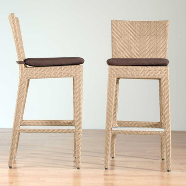 Two wicker bar stools with brown cushions on a light wooden floor.