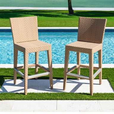 Two wicker bar stools by a poolside on a sunny day.