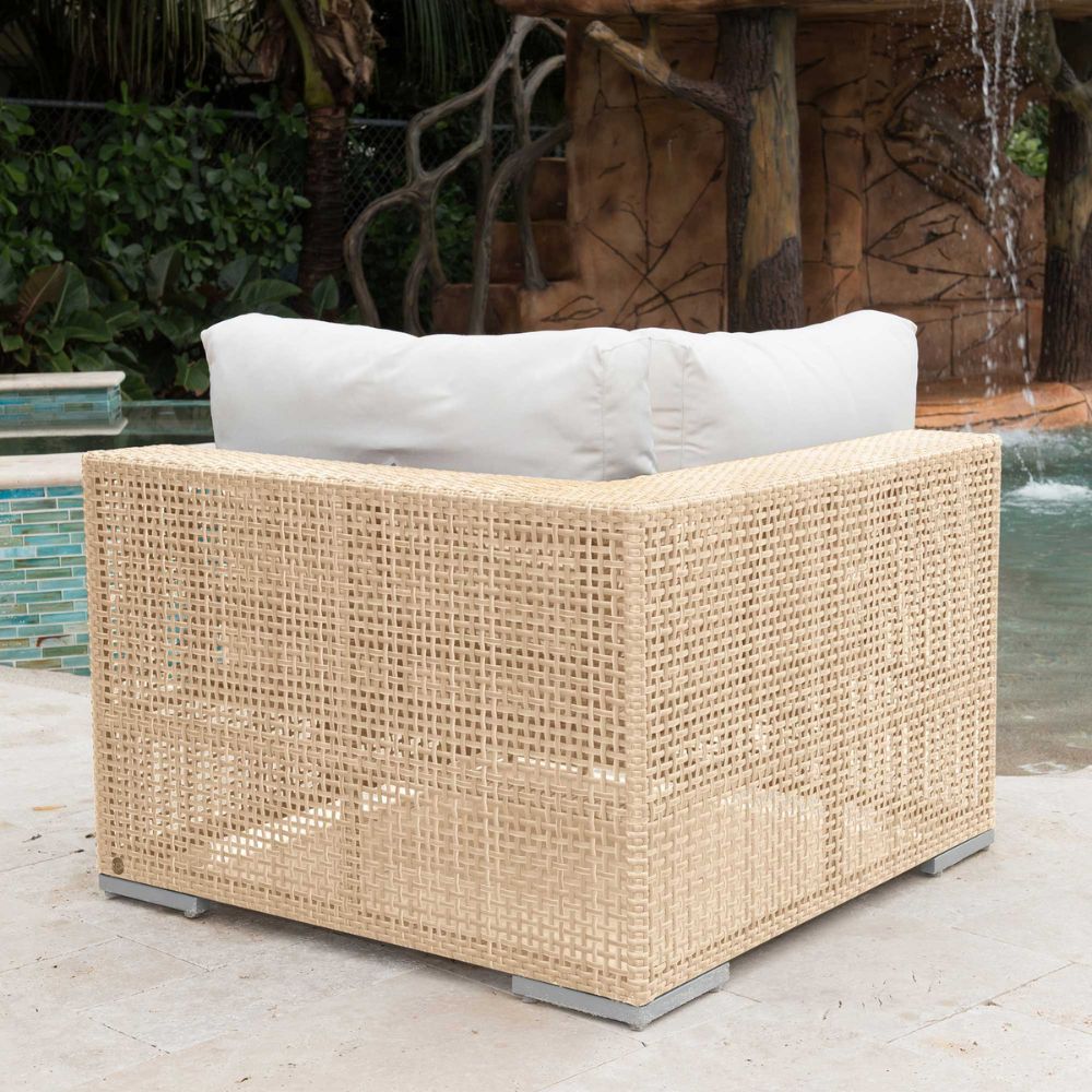 Wicker outdoor chair with white cushions by a poolside