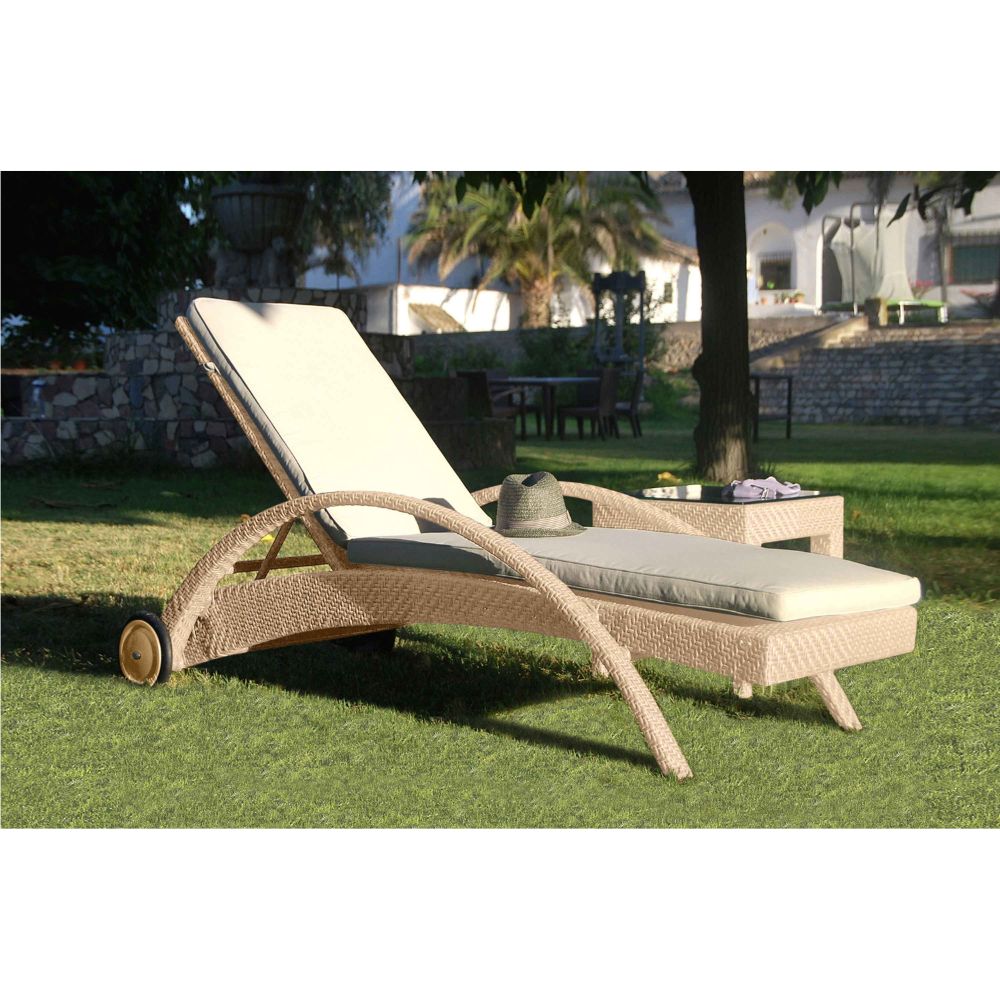Wicker sun lounger with beige cushion on a grassy area