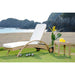 White lounge chair with a small table and decorative items on a grassy area with a scenic background.