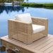 Wicker chair with white cushion on a wooden deck by a body of water
