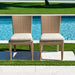Two wicker chairs with beige cushions by a poolside.