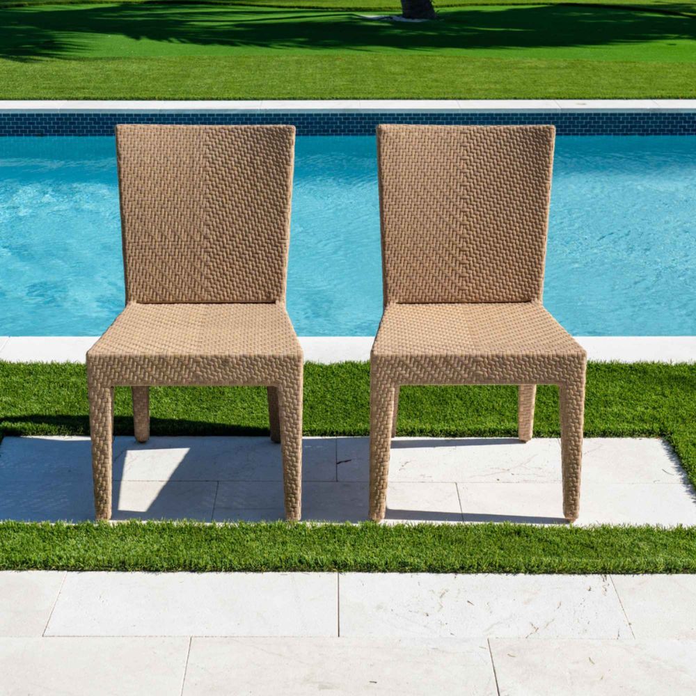 Two wicker chairs by a pool with grass and water in the background