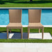 Two wicker chairs by a pool with grass and water in the background