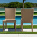 Two wicker chairs by a pool with greenery in the background
