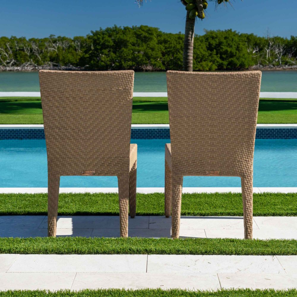 Two wicker chairs by a pool with a scenic background