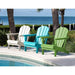 Three Adirondack chairs in white, blue, and green by a pool with ocean view.