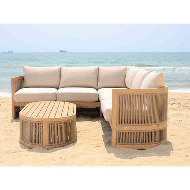 Outdoor furniture set with beige sofa, chair, and table on a sandy beach.