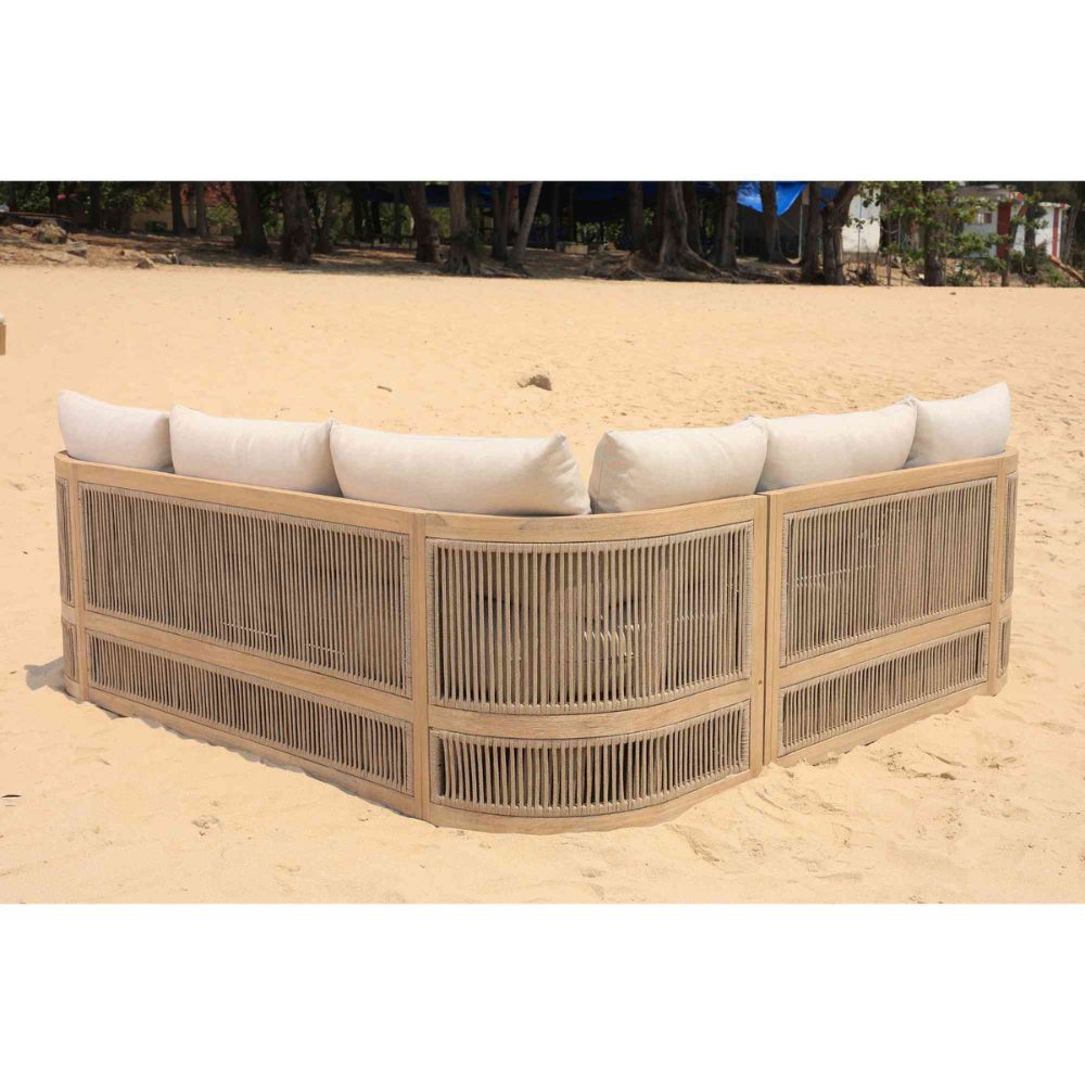 Wicker bench with white cushions on a sandy beach