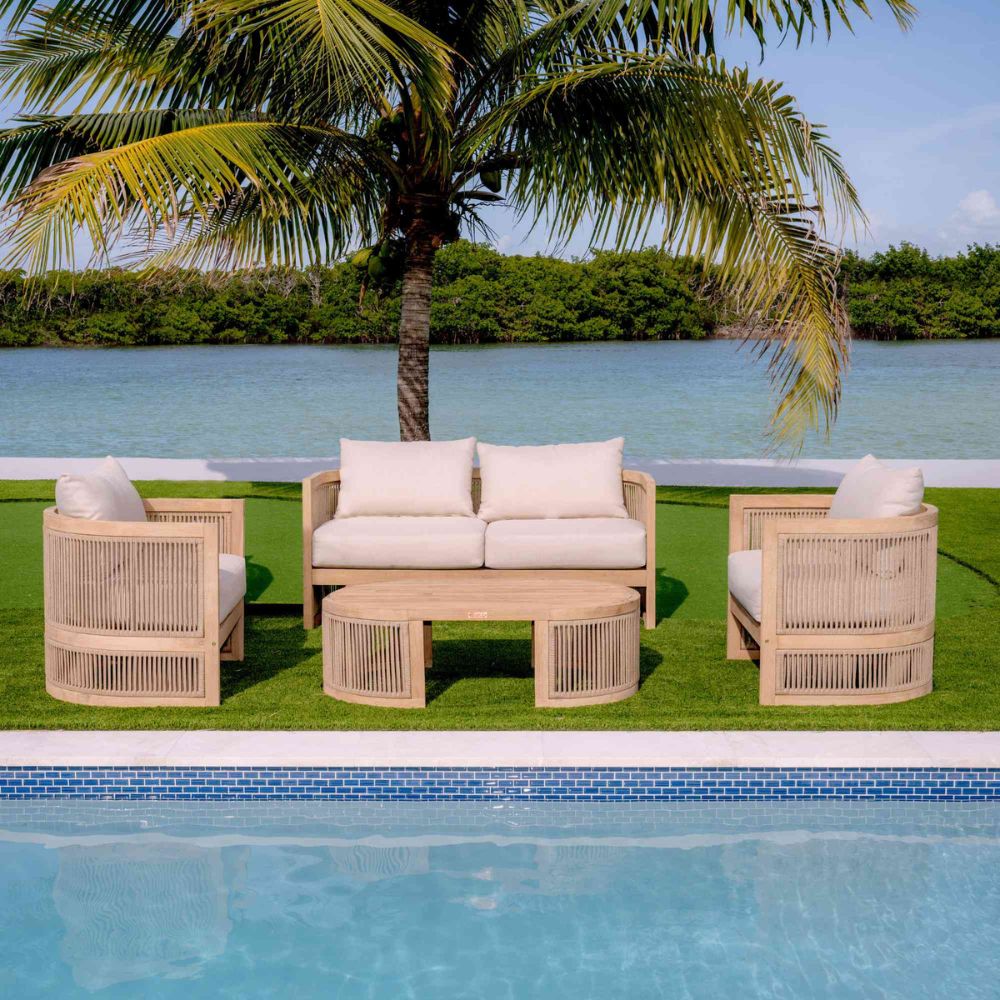 Outdoor patio set with beige chairs and white cushions by a pool and palm tree.