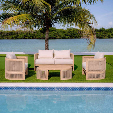 Outdoor patio set with beige chairs and white cushions by a pool and palm tree.