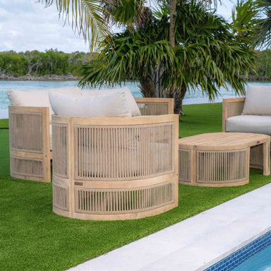 Outdoor furniture set with wooden frames and white cushions by a poolside.