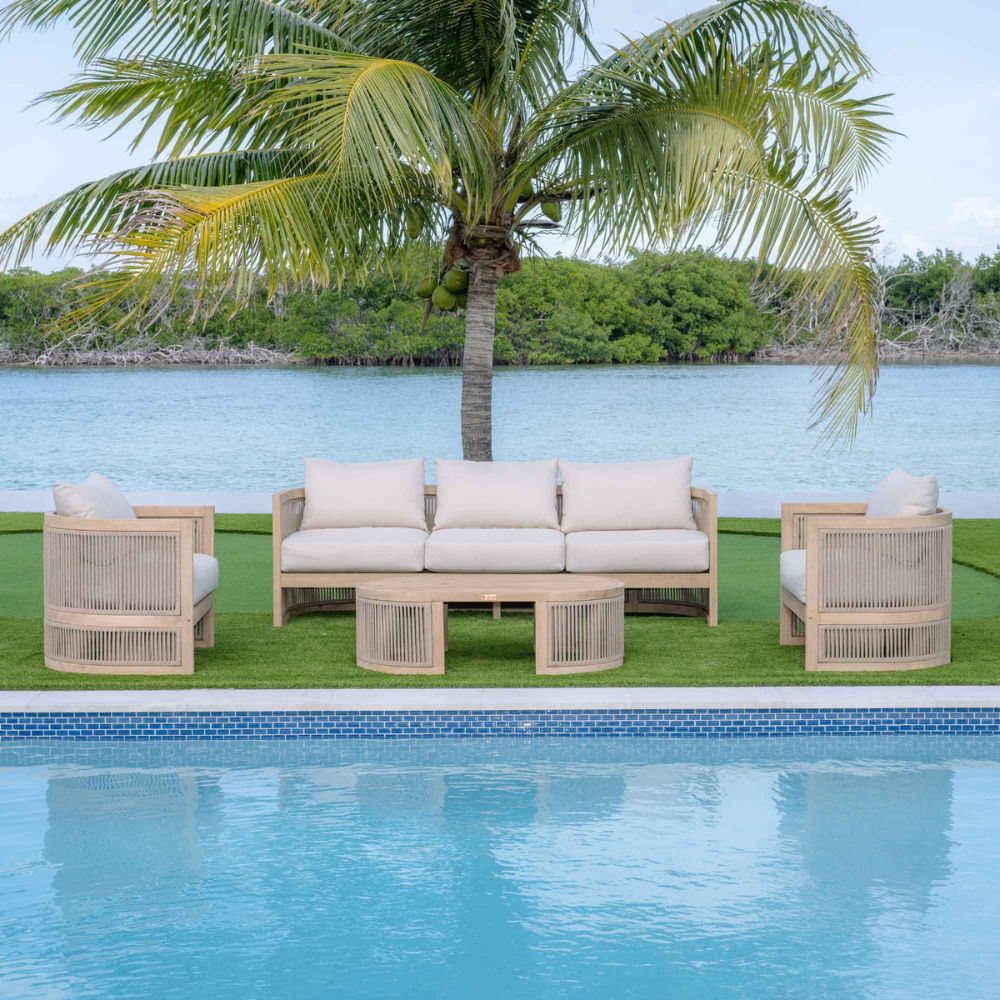 Outdoor patio set with beige frames and white cushions by a pool and palm tree.