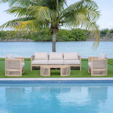 Outdoor patio set with beige frames and white cushions by a pool and palm tree.