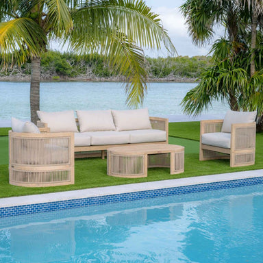 Outdoor furniture set with beige cushions by a poolside with palm trees and water in the background