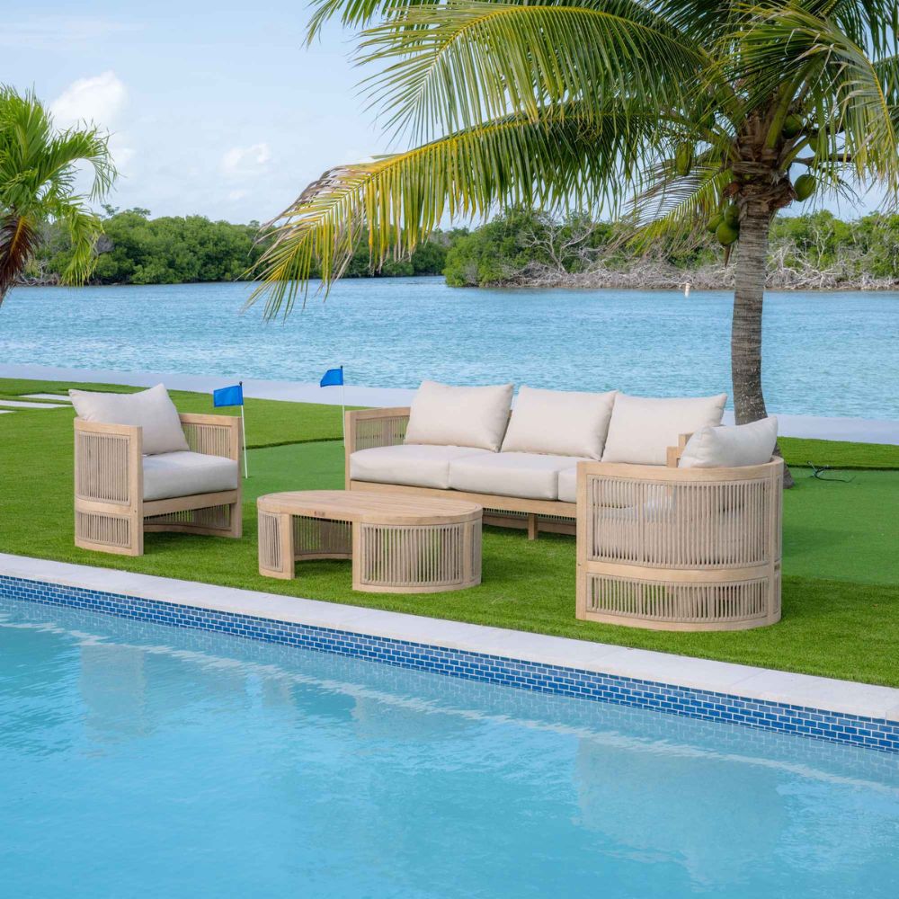 Outdoor furniture set by a pool with palm trees and water in the background