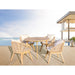 Outdoor furniture set with a round table and four chairs on a deck with a pool and ocean view.