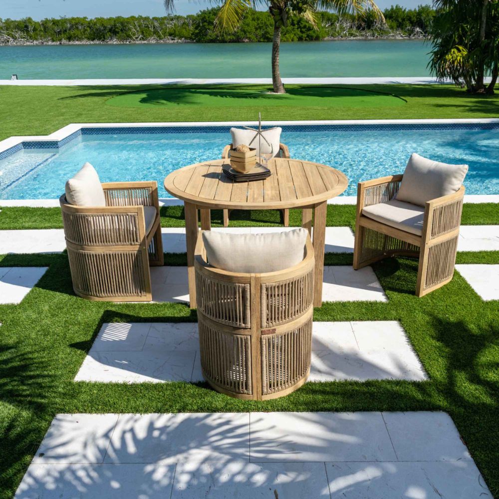 Outdoor patio set with wooden furniture and cushions by a poolside.