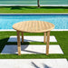 Wooden round table on grass near a pool
