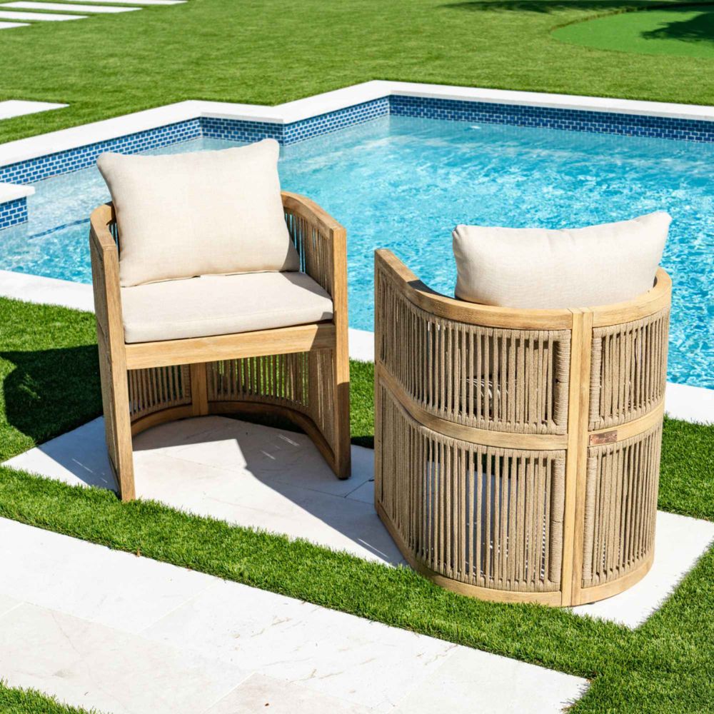 Two wooden chairs with white cushions by a pool