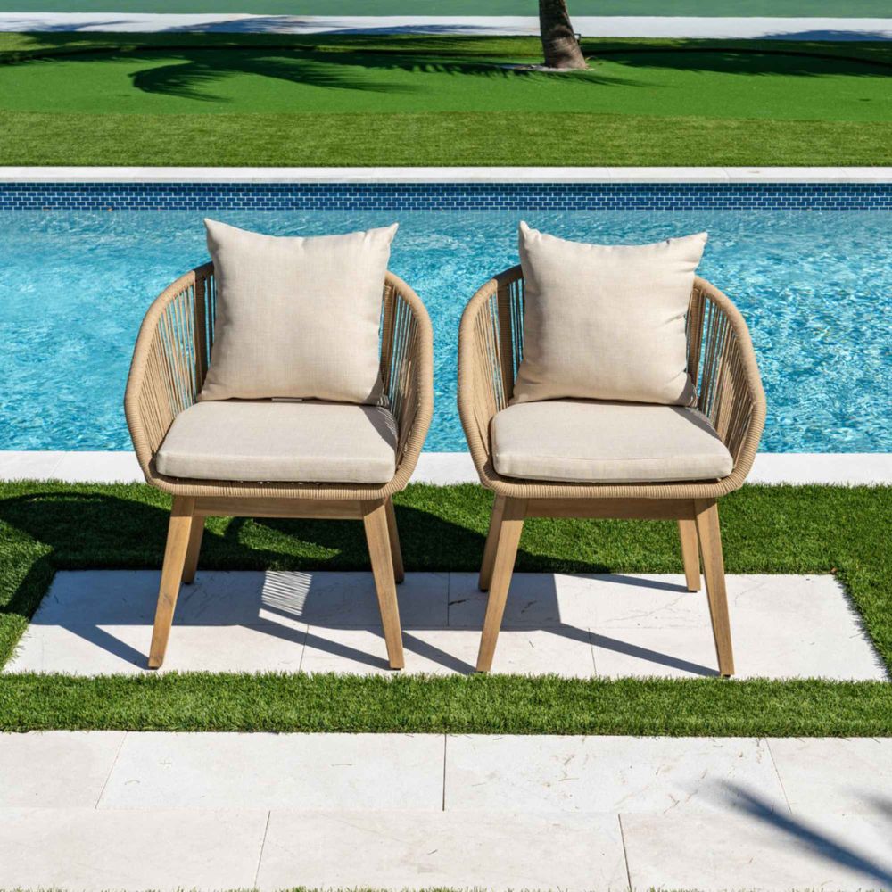 Two wooden chairs with beige cushions by a poolside.