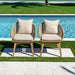 Two wooden chairs with beige cushions by a poolside.