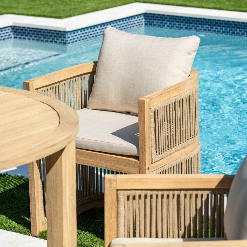 Wooden outdoor furniture set with beige cushions by a pool