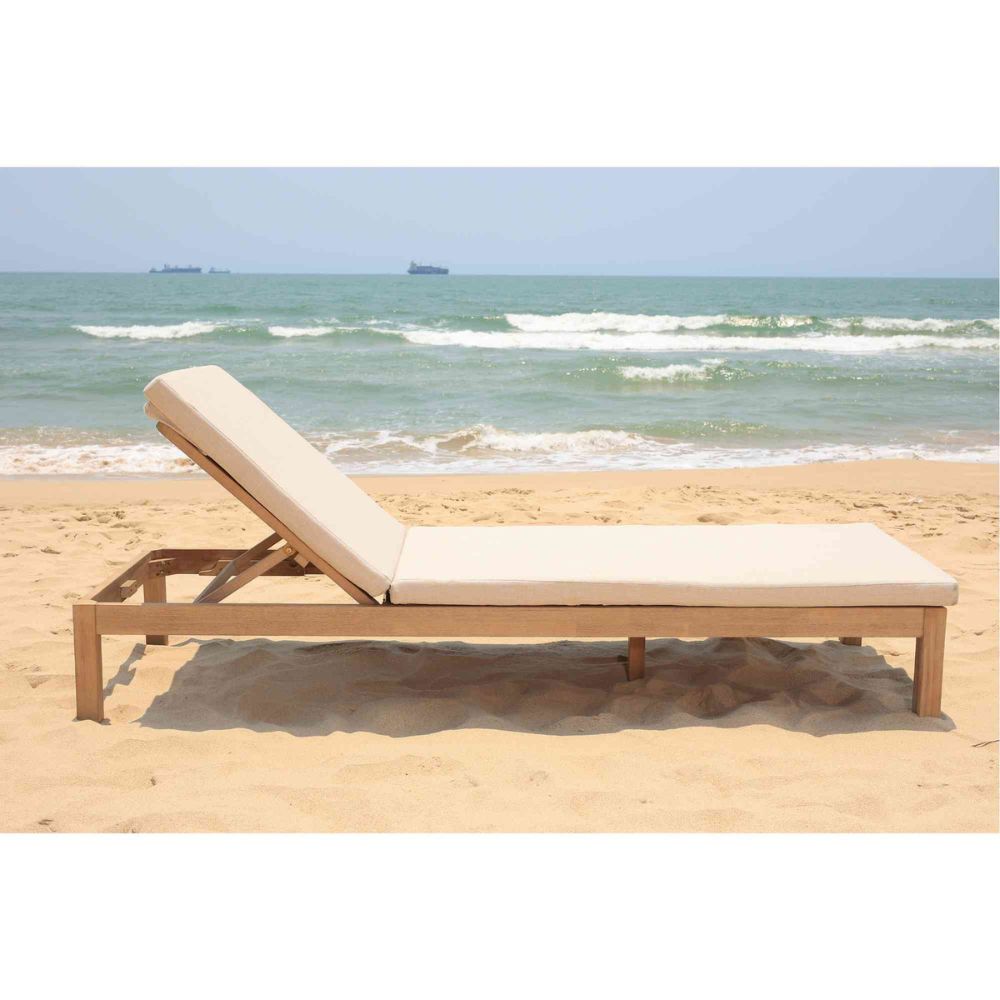 Beach chair with beige cushion on a sandy beach with ocean view
