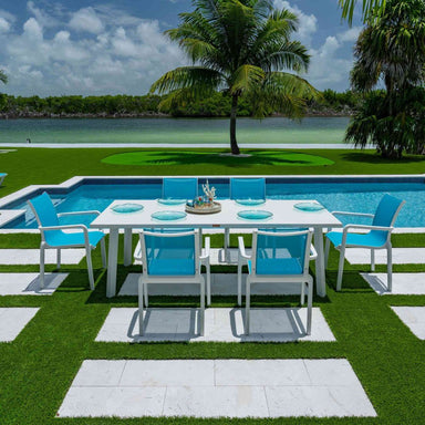 Outdoor dining setup with a table and blue chairs by a poolside.