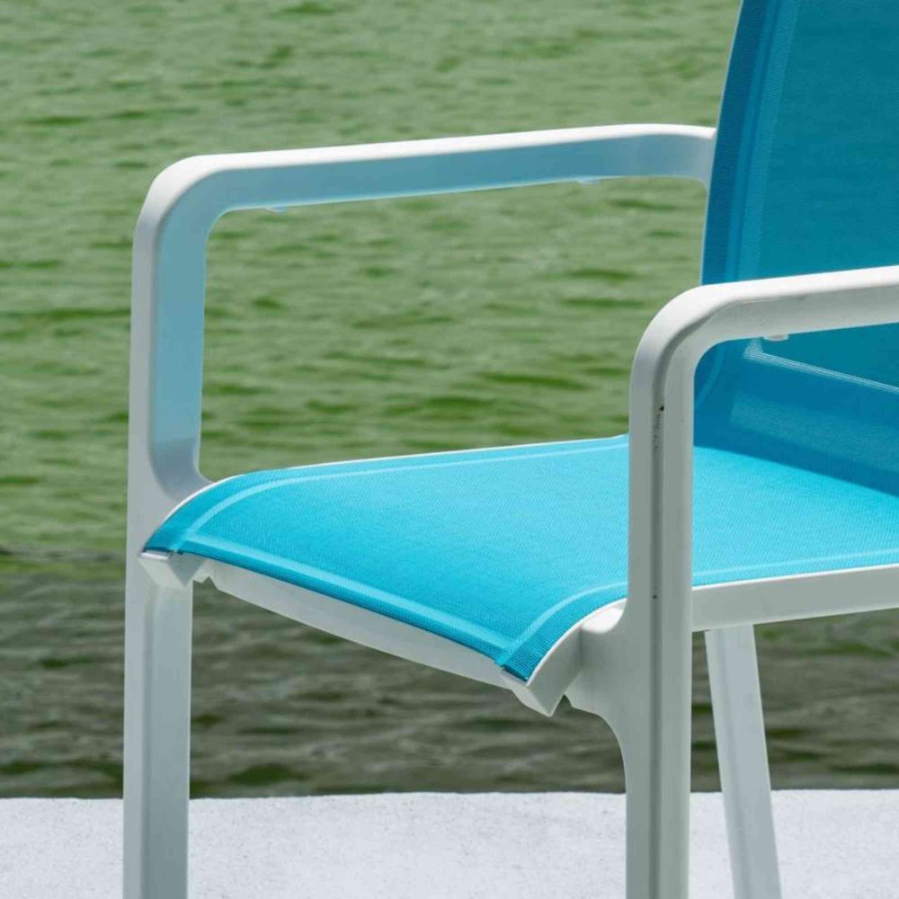 Blue chair with white frame by a body of water