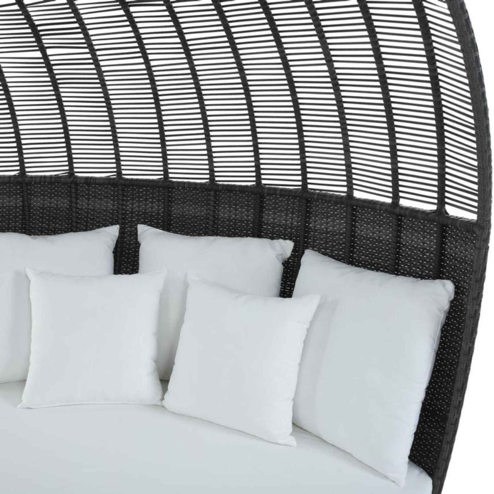 Bed with white bedding and pillows against a black woven headboard.