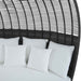 Bed with white bedding and pillows against a black woven headboard.