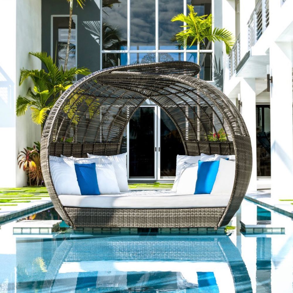 Wicker daybed with white and blue cushions by a poolside