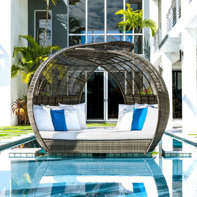 Wicker daybed with white and blue cushions by a poolside
