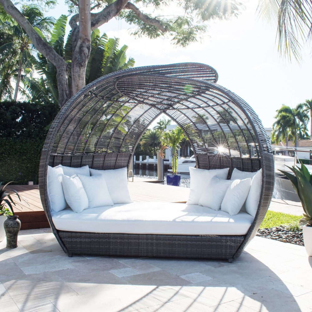 Wicker outdoor daybed with white cushions on a patio