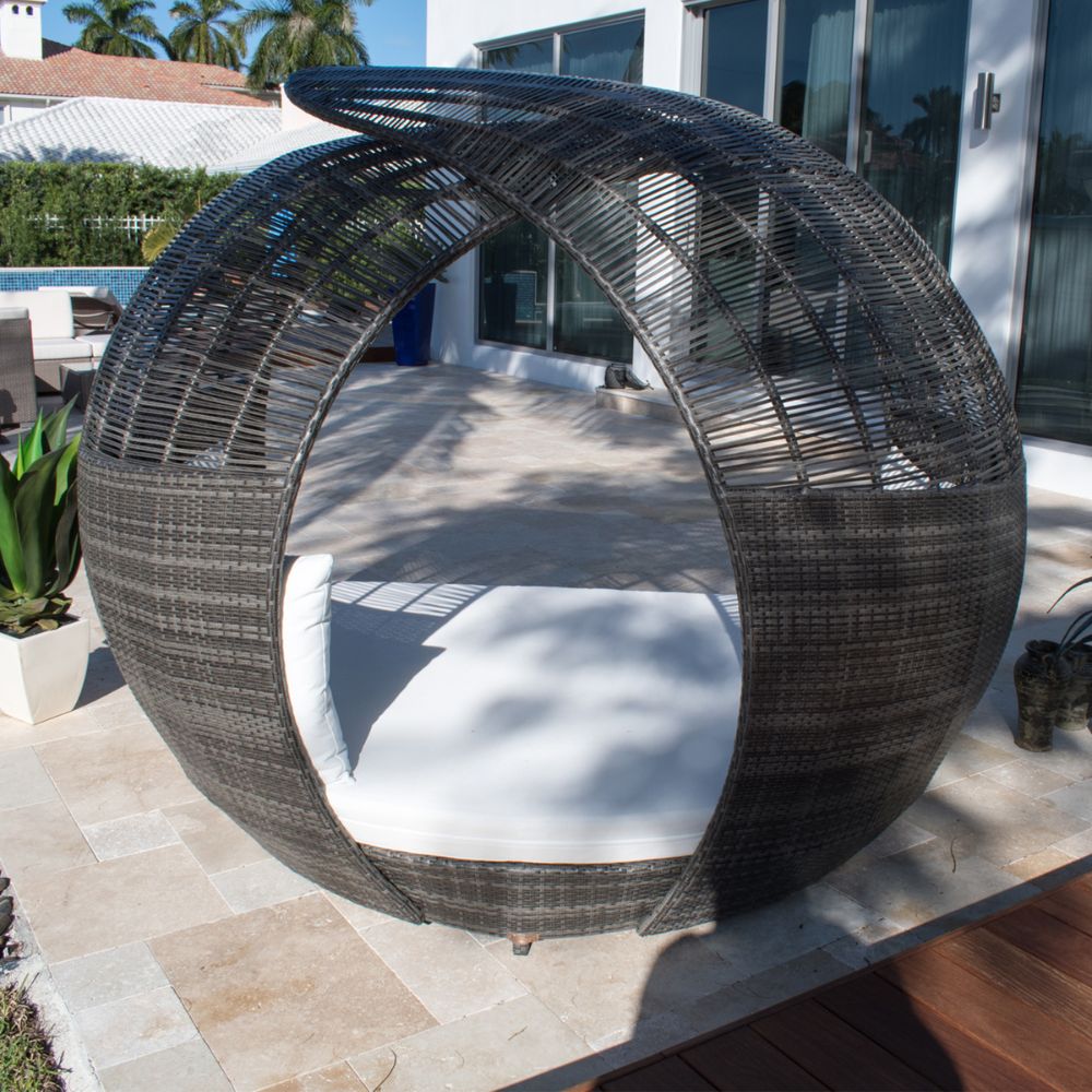 Wicker outdoor pod with white cushion on a patio