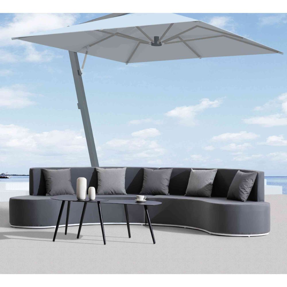 Modern outdoor sofa set with a large umbrella against a blue sky.