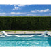 White lounge chair in a pool with a hedge and blue sky background