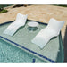Two white lounge chairs and a small round table by a poolside.