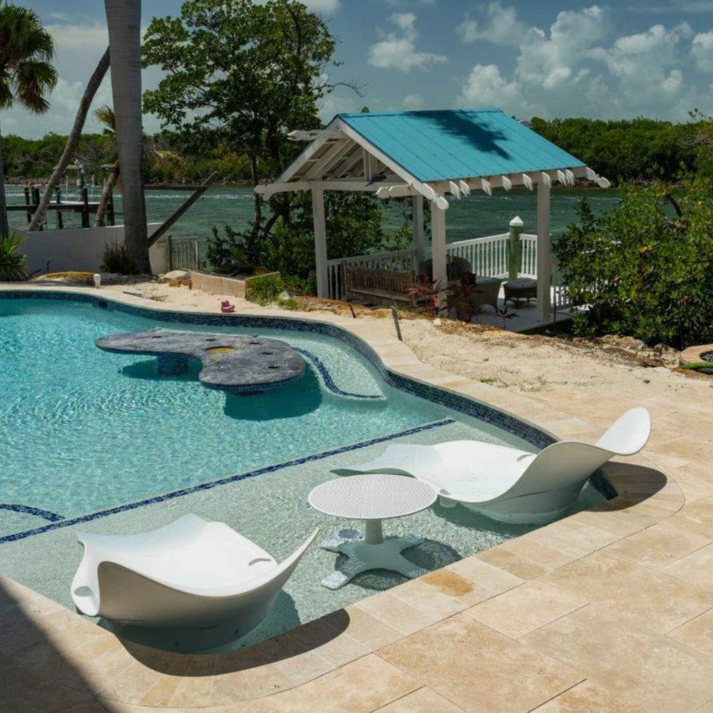 Pool area with lounge chairs and a gazebo by a waterfront