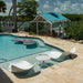 Pool area with lounge chairs and a gazebo by a waterfront